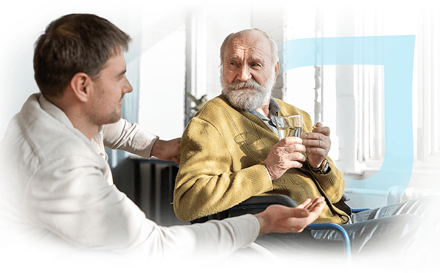 SafeLife caregiver sharing a glass of water with a senior man in a wheelchair at home
